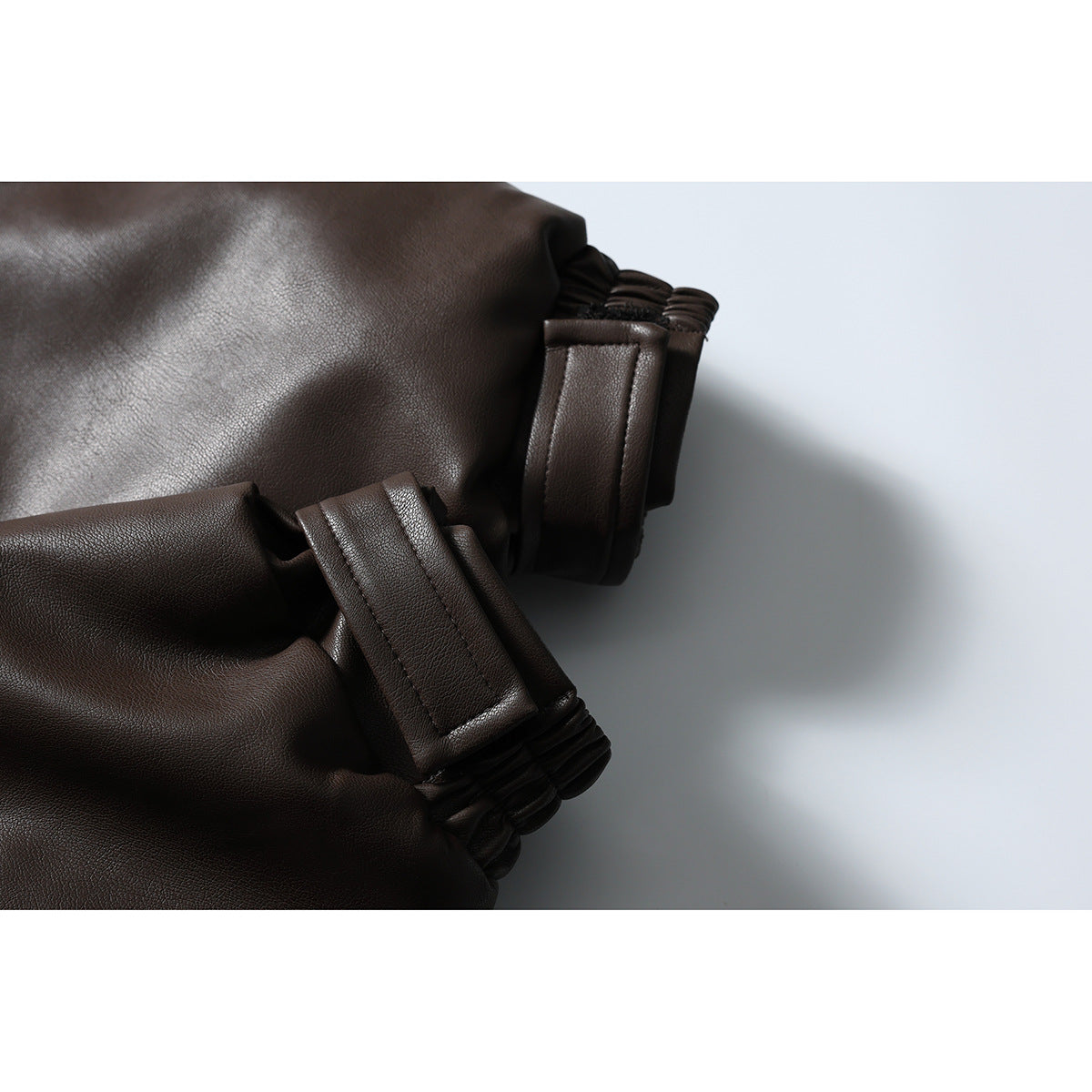 Close-up of the dark brown jacket's sleeve cuff, showing a tab and gathered elastic edge.
