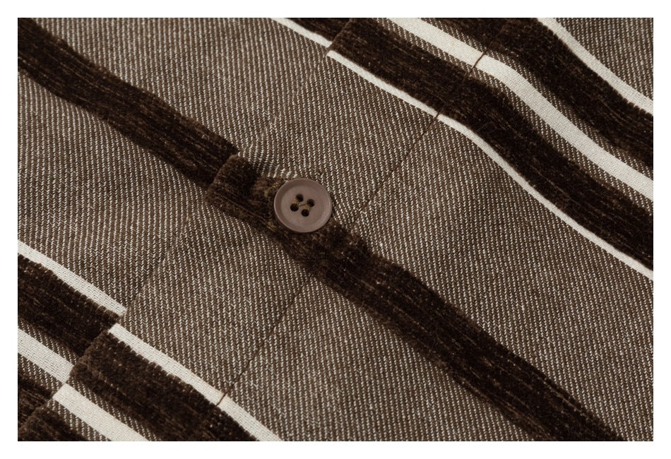 Close-up of a brown button on taupe fabric with dark brown and cream stripes.