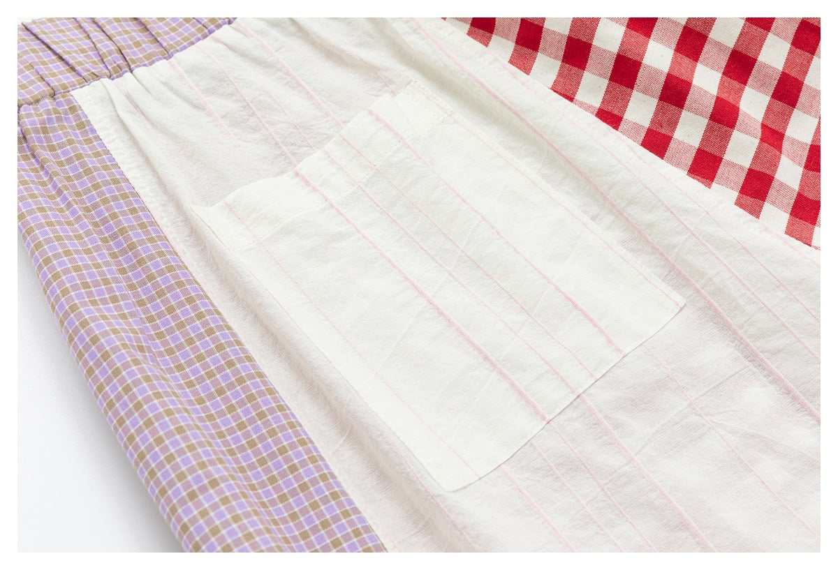 Close-up of a white panel with a rectangular pocket and fine pink stripes, bordered by lavender and red gingham fabric.