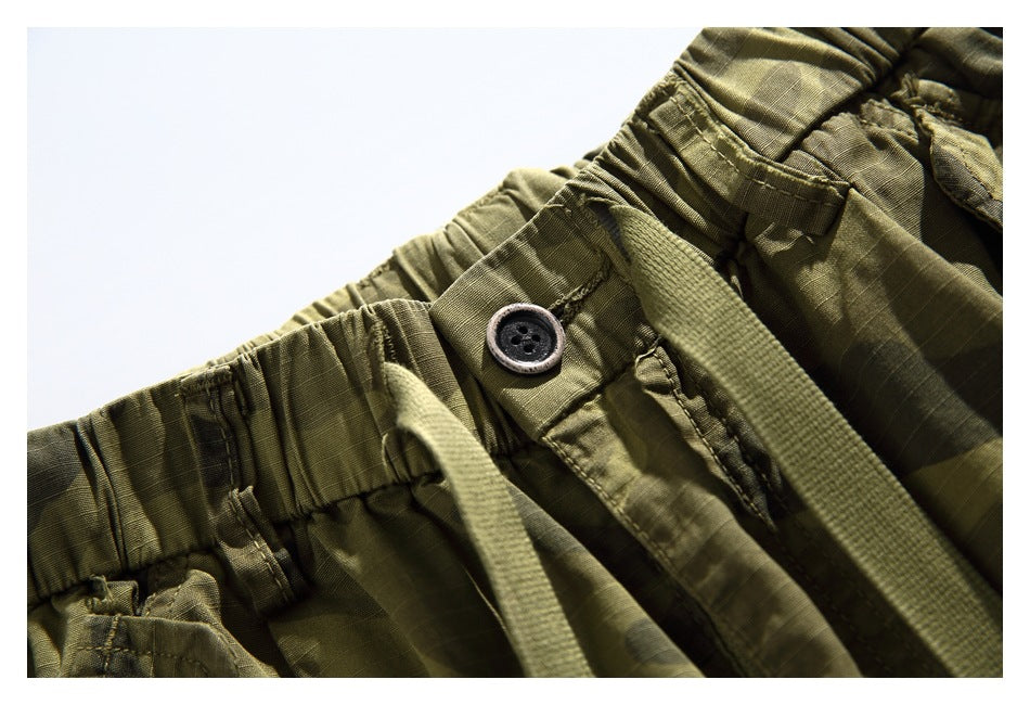 Close-up of the shorts' button, drawstring, elastic waistband, and camouflage fabric.