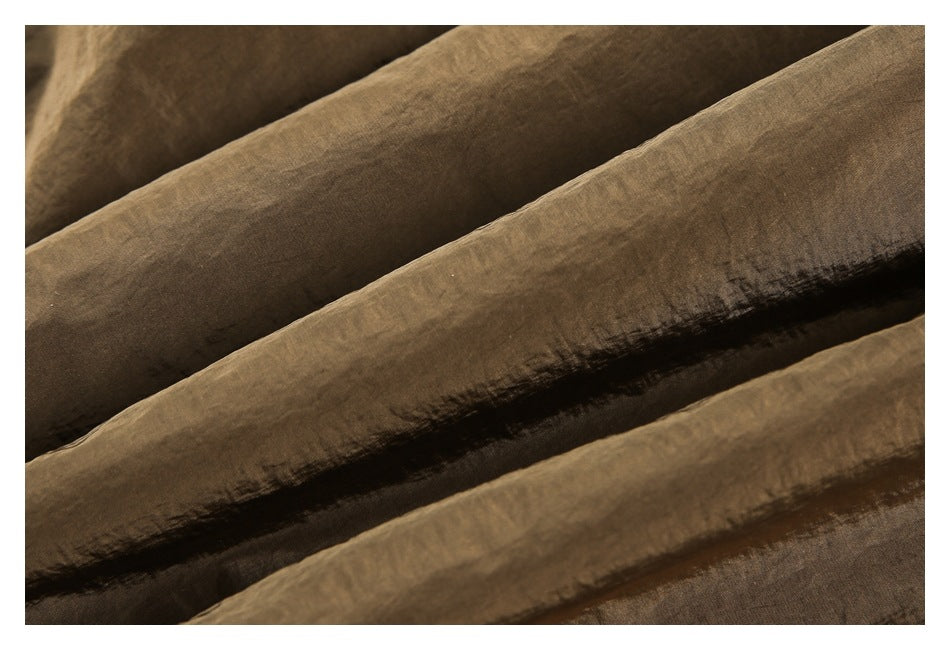Extreme close-up of the brown trousers' softly crinkled fabric texture.