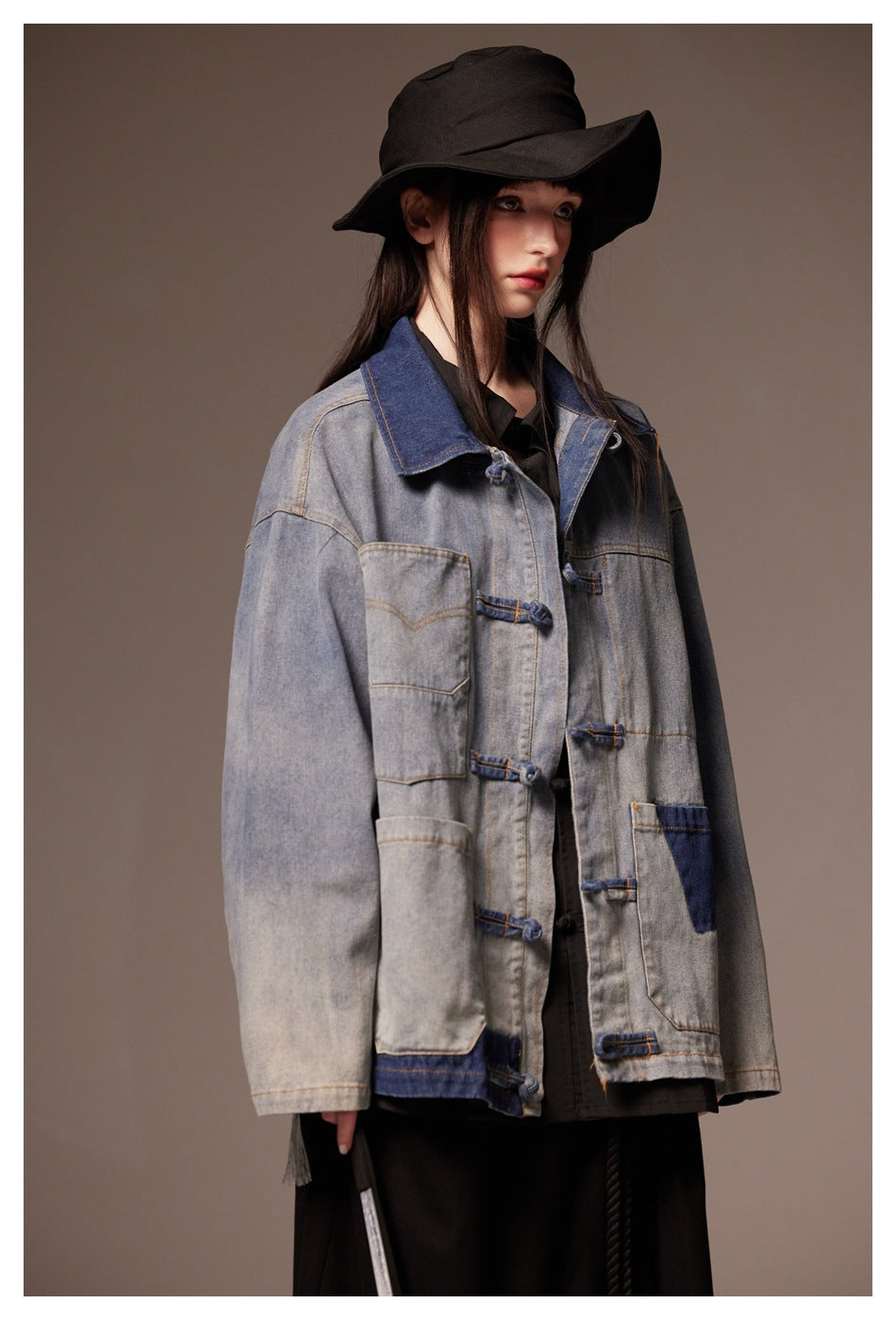 Close three-quarter view of model wearing washed denim jacket with contrast collar and knotted frog closures