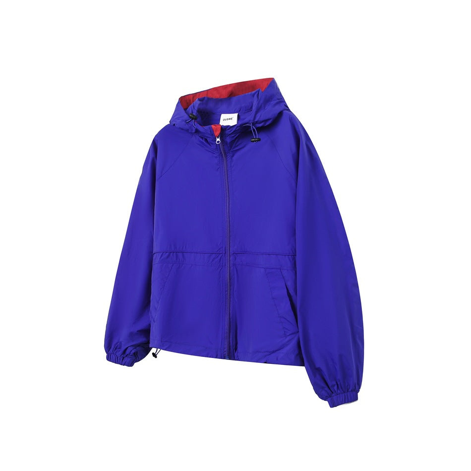 Blue hooded zip-up jacket with red hood lining, front pockets and elastic cuffs, shown from a three-quarter front angle