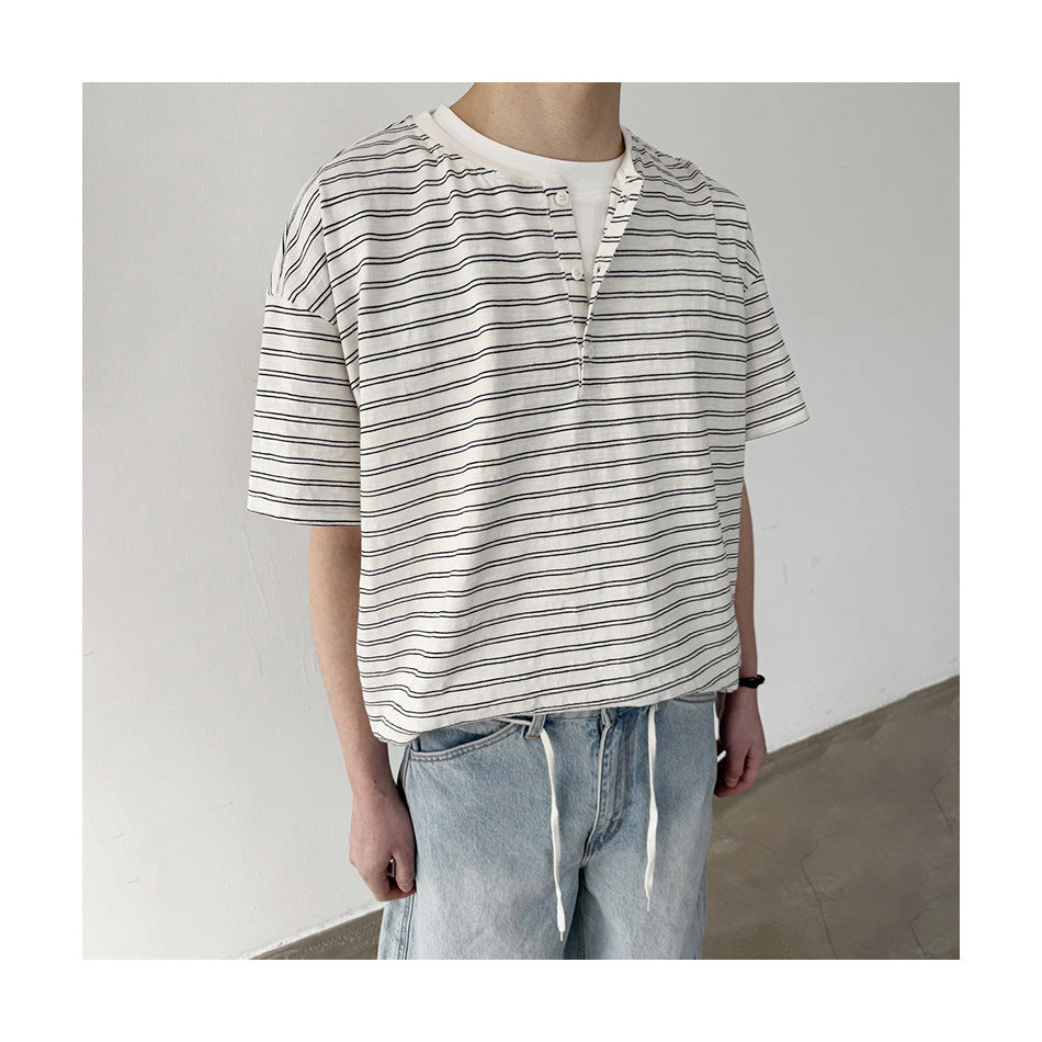 Cropped view of a person wearing a loose white short-sleeve henley with thin black horizontal stripes.