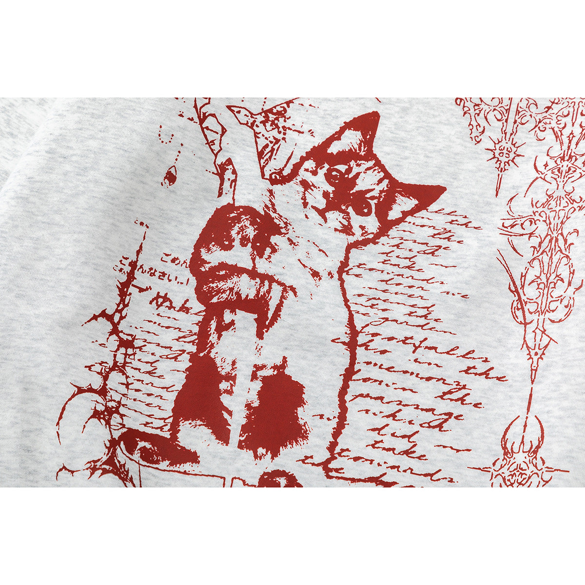 Close-up of a red cat illustration and ornate script-like artwork printed on light heather-gray sweatshirt fabric.