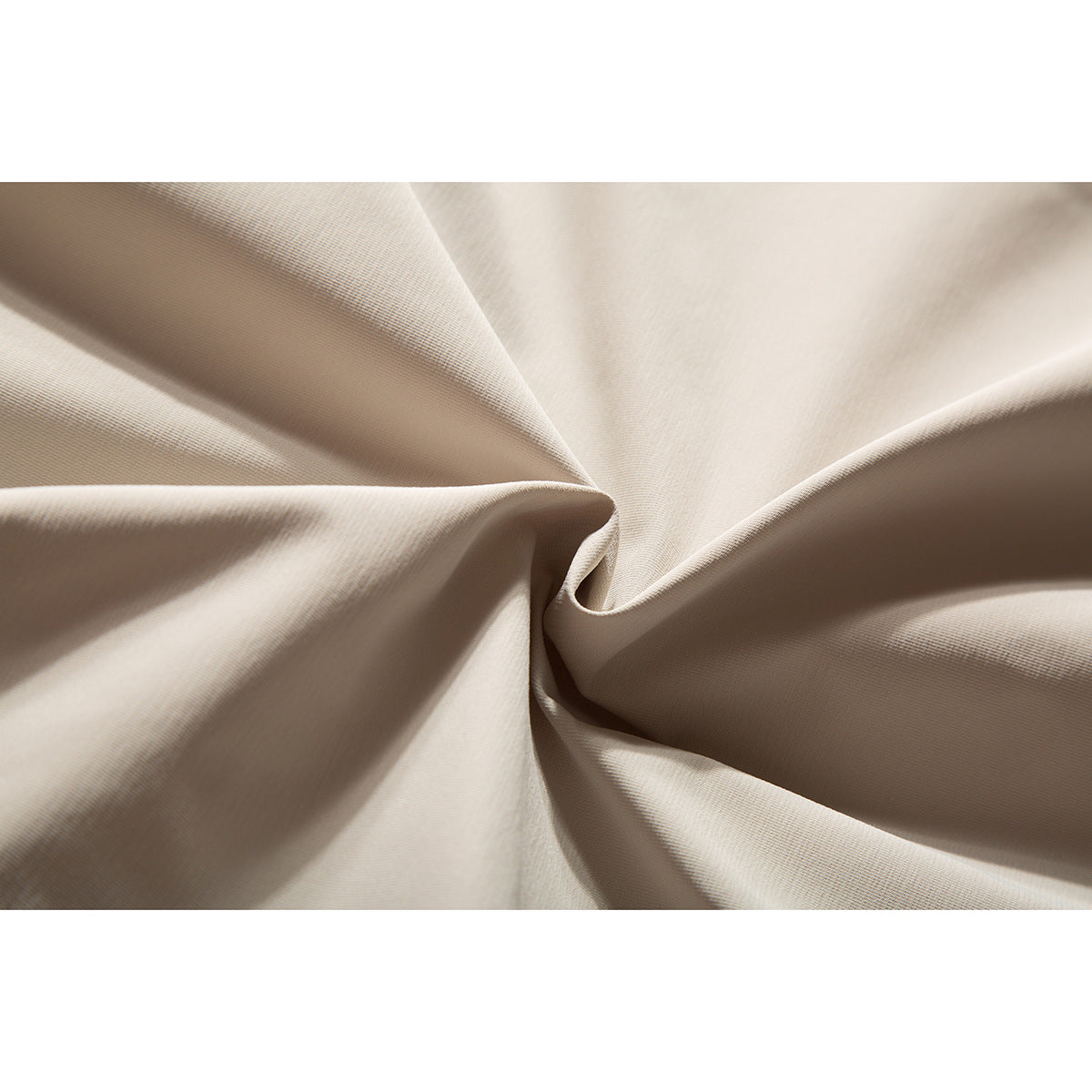 Close-up of light beige fabric gathered into folds, showing its fine surface texture.