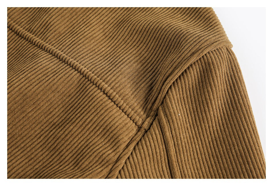 Close-up of brown ribbed jacket fabric and a curved stitched seam.