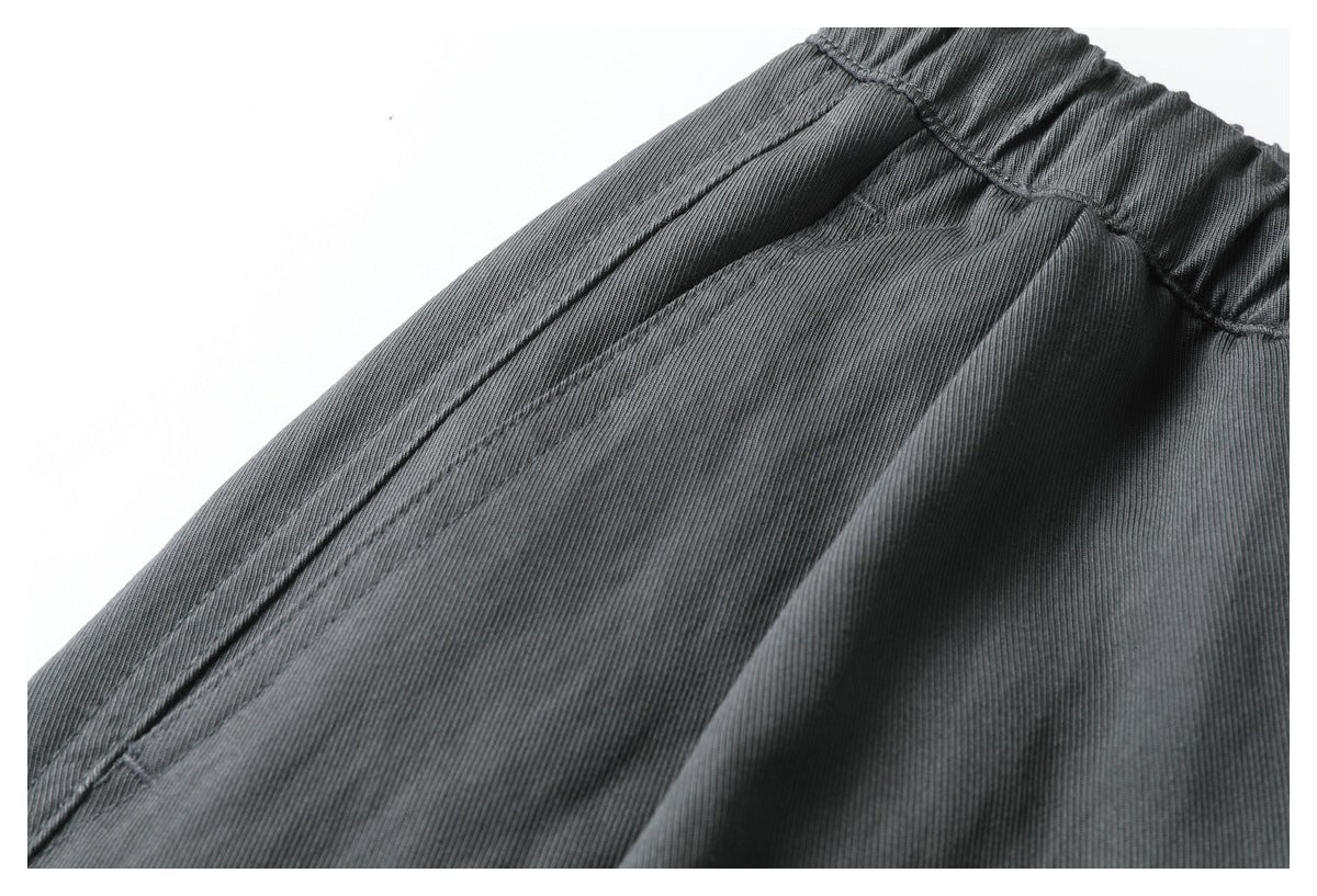 Close-up of charcoal gray pants showing the gathered elastic waistband and stitched seams.