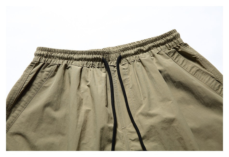 Close-up of the shorts' elastic waistband, black drawstrings and front stitching.