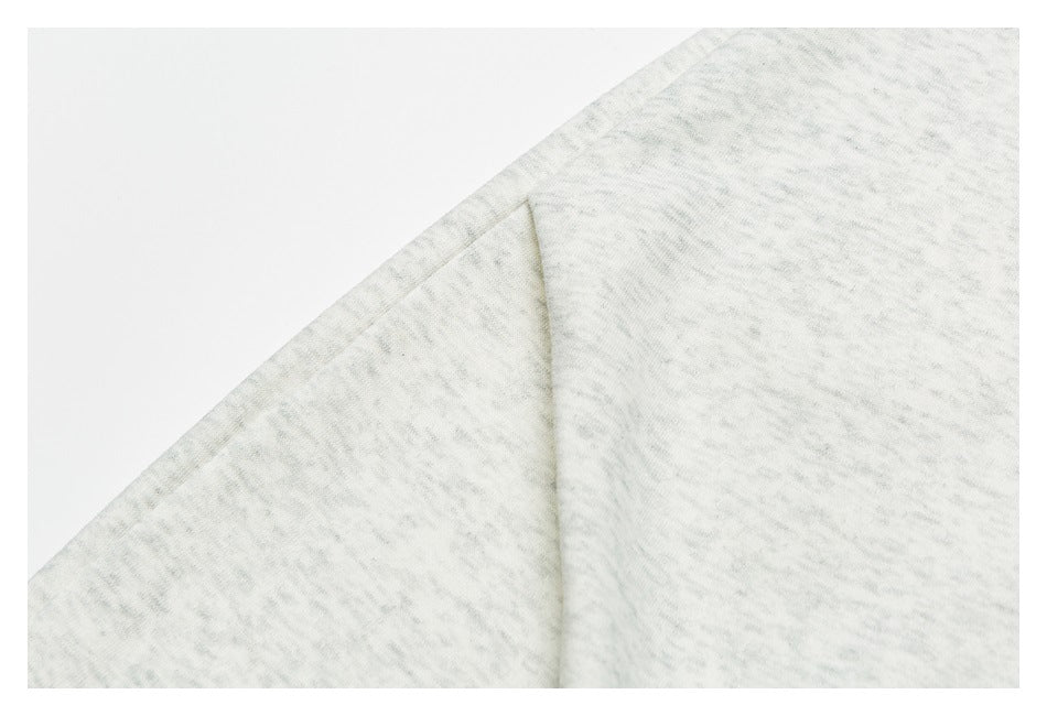 Close-up of light gray mottled garment fabric folded along a diagonal edge.