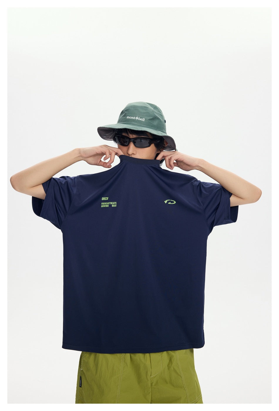 Model holds up the front of a navy oversized T-shirt, showing its small lime chest graphics.