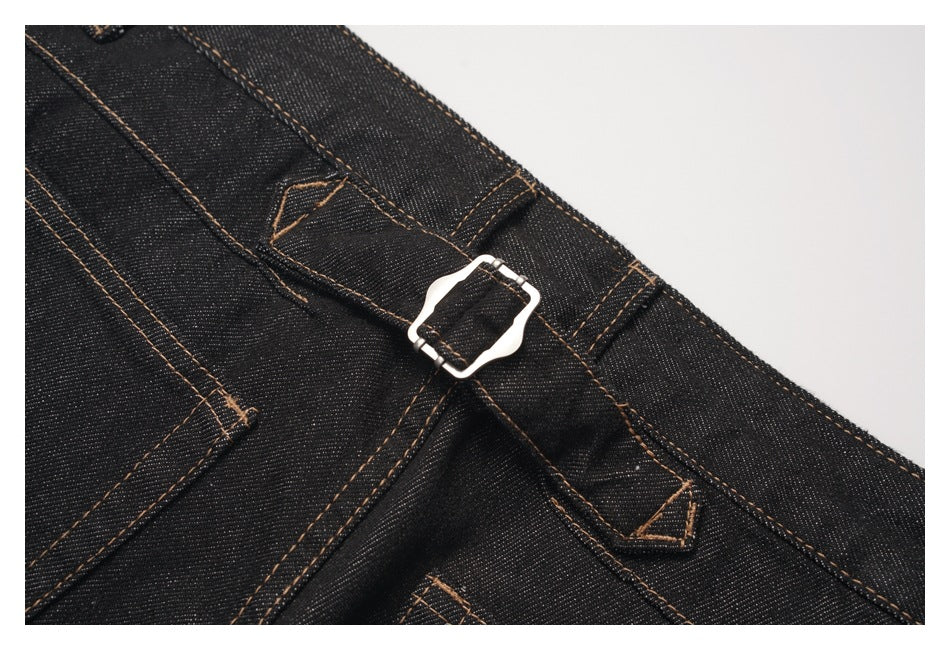Close-up of a silver buckle fastened over a black denim waistband with tan stitching.