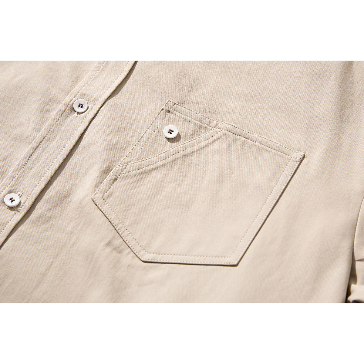 Close-up of a beige shirt's angular chest pocket, white button, and placket.