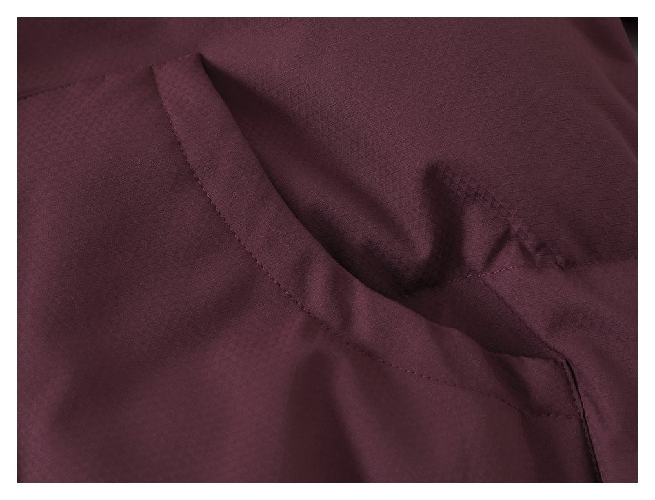 Close-up of a slanted welt pocket on the textured burgundy jacket.