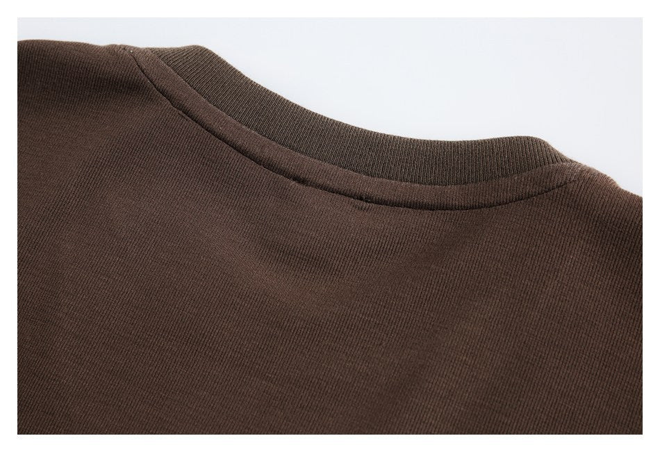 Close-up of the crew neckline and collar seam on a brown rib-knit top.