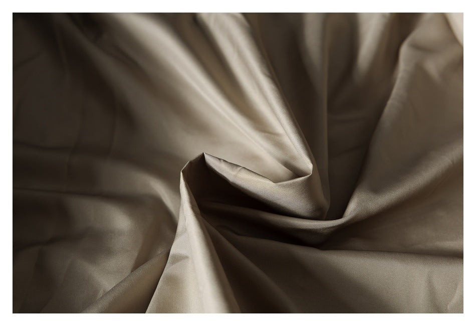 Close-up of smooth taupe fabric draped into soft folds.