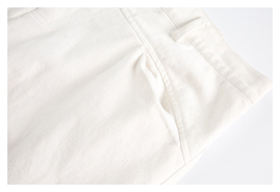 Close-up of ivory trouser fabric, stitching, and a side seam near the waistband.
