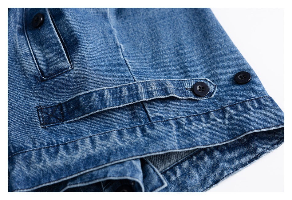 Close-up of blue denim with black buttons, a buttoned tab, and stitched seams.
