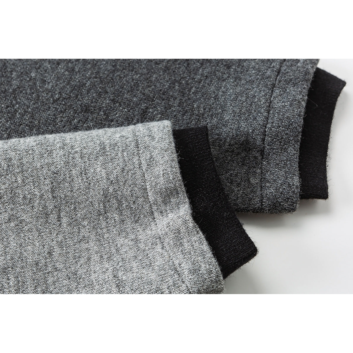 Close-up of gray sleeves with black cuffs and layered garment edges.