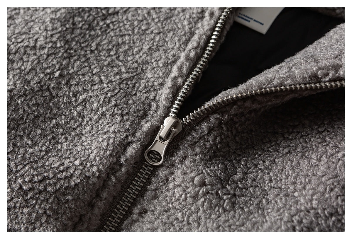 Close-up of the gray jacket's front zipper, textured fabric and inner label.