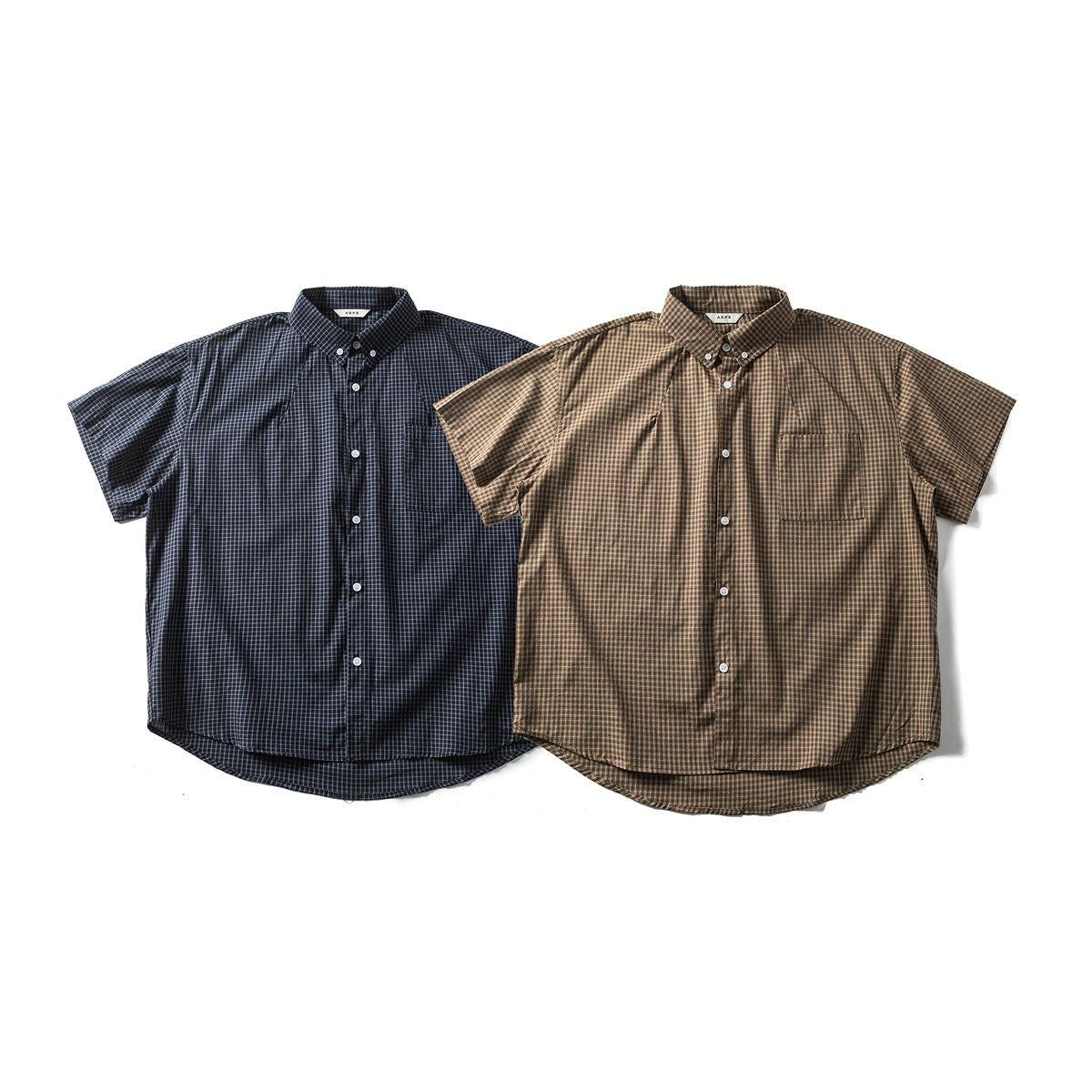 Front view of two short-sleeve button-up shirts: one navy plaid and one brown plaid, each with a chest pocket.