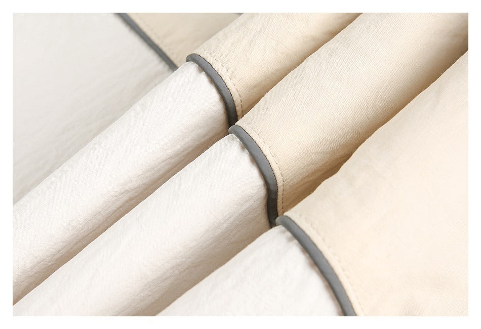 Close-up of cream jacket sleeves with gray piping at the cuff seams.