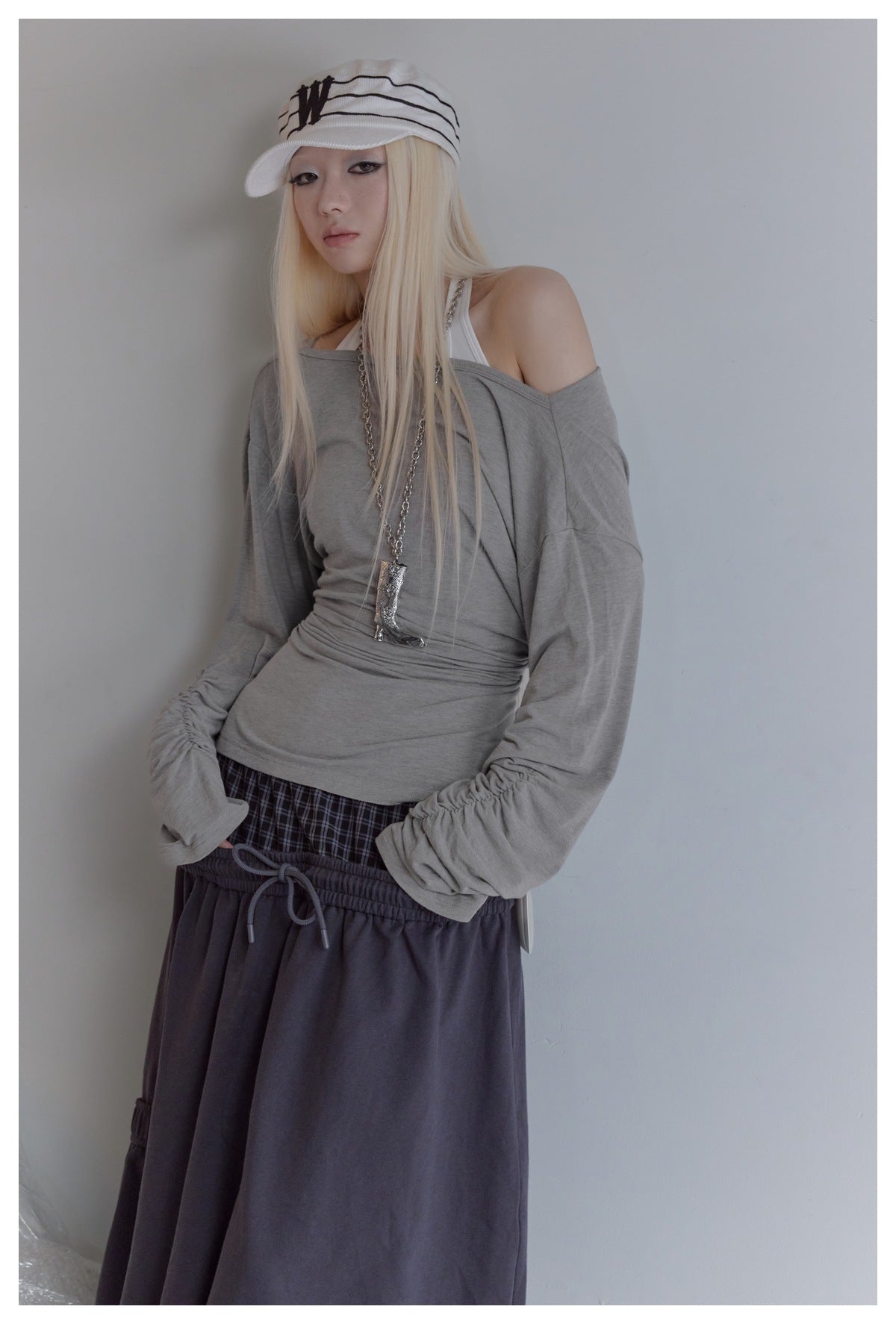 Closer view of a model wearing a gray off-shoulder top with gathered sleeves and dark layered bottoms.