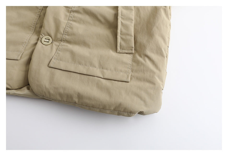 Close-up of a beige garment with a flap pocket, button, and visible stitching.