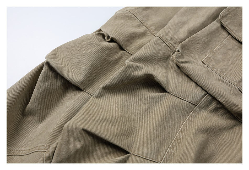 Close-up of khaki cargo pants showing layered leg panels, seams, and part of a flap pocket.
