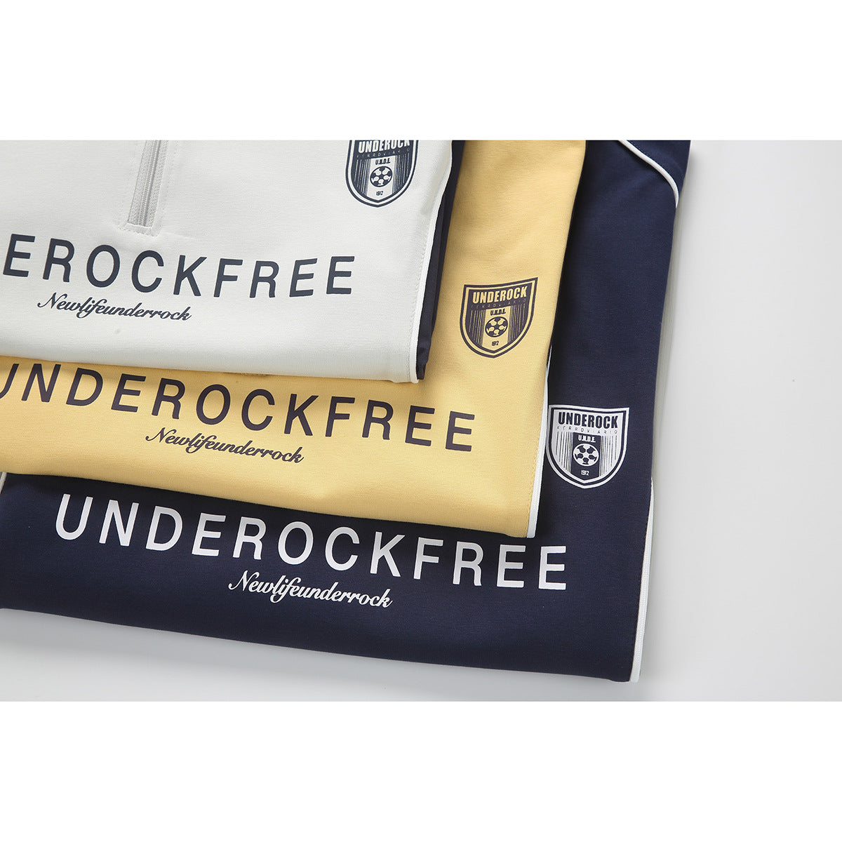 Folded white, yellow, and navy polo shirts with large lettering and crest graphics.
