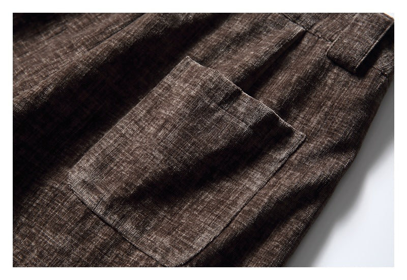 Close-up of a large patch pocket on brown crosshatched trousers.