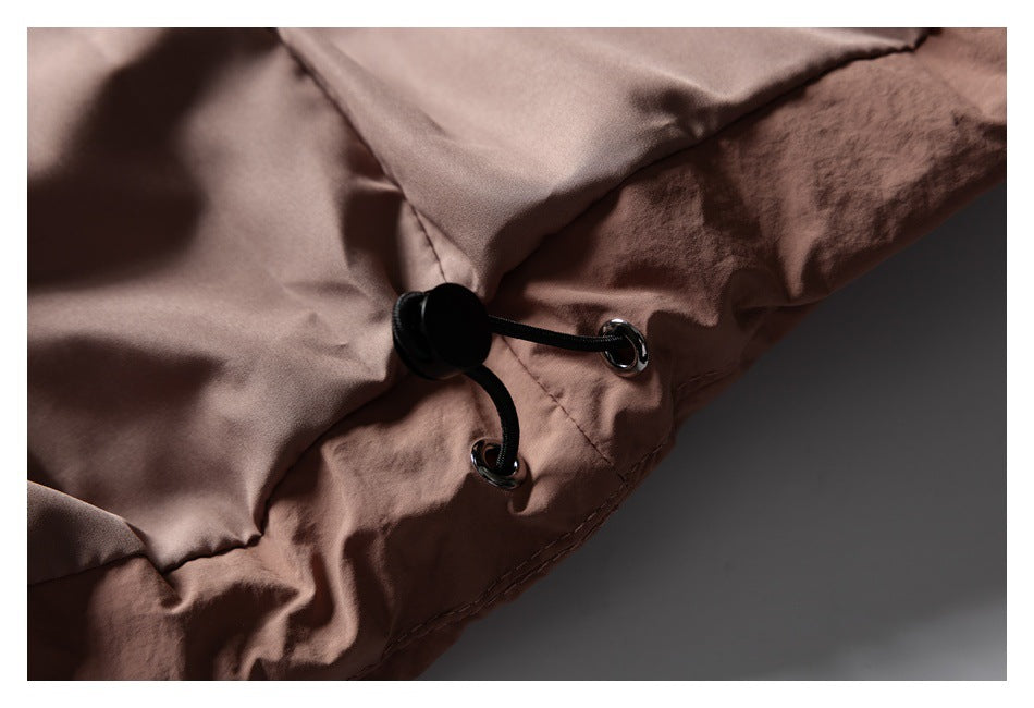 Close-up of a black adjustable drawcord and metal eyelets on the dusty rose jacket.