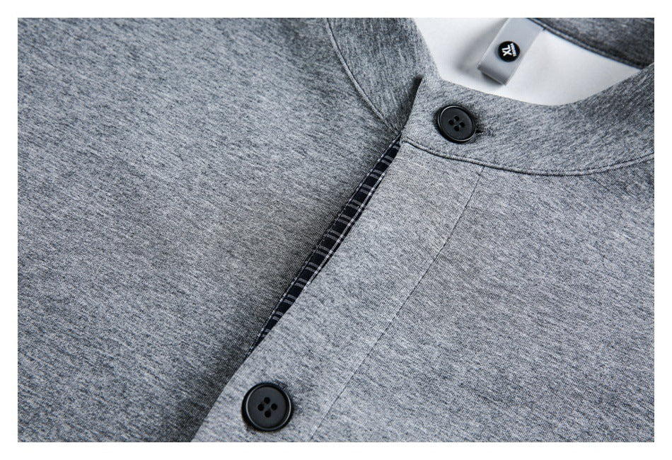 Close-up of a gray garment showing black buttons and a narrow dark plaid strip along a seam.