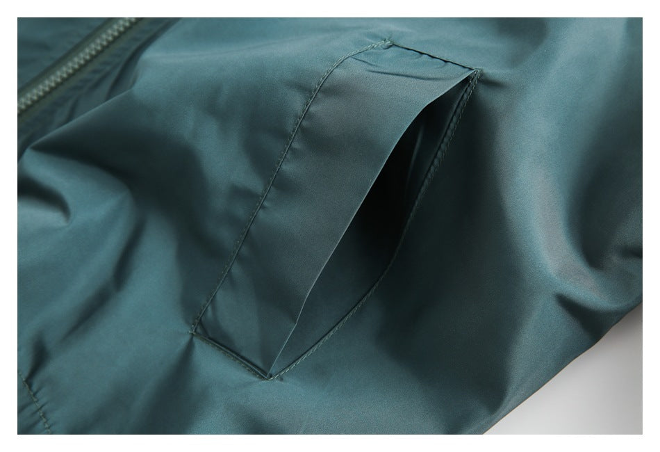 Close-up of a teal garment's angled welt pocket and nearby zipper.