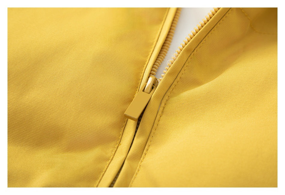 Close-up of the mustard-yellow jacket's zipper, stitching, and fabric.