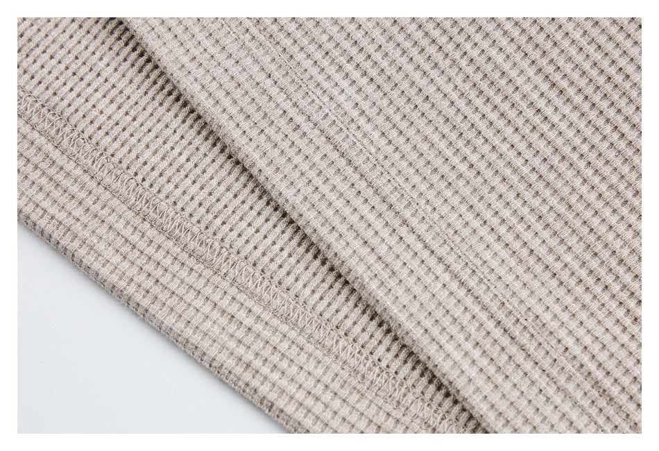 Close-up of the beige textured top's folded edge and visible overlock stitching.