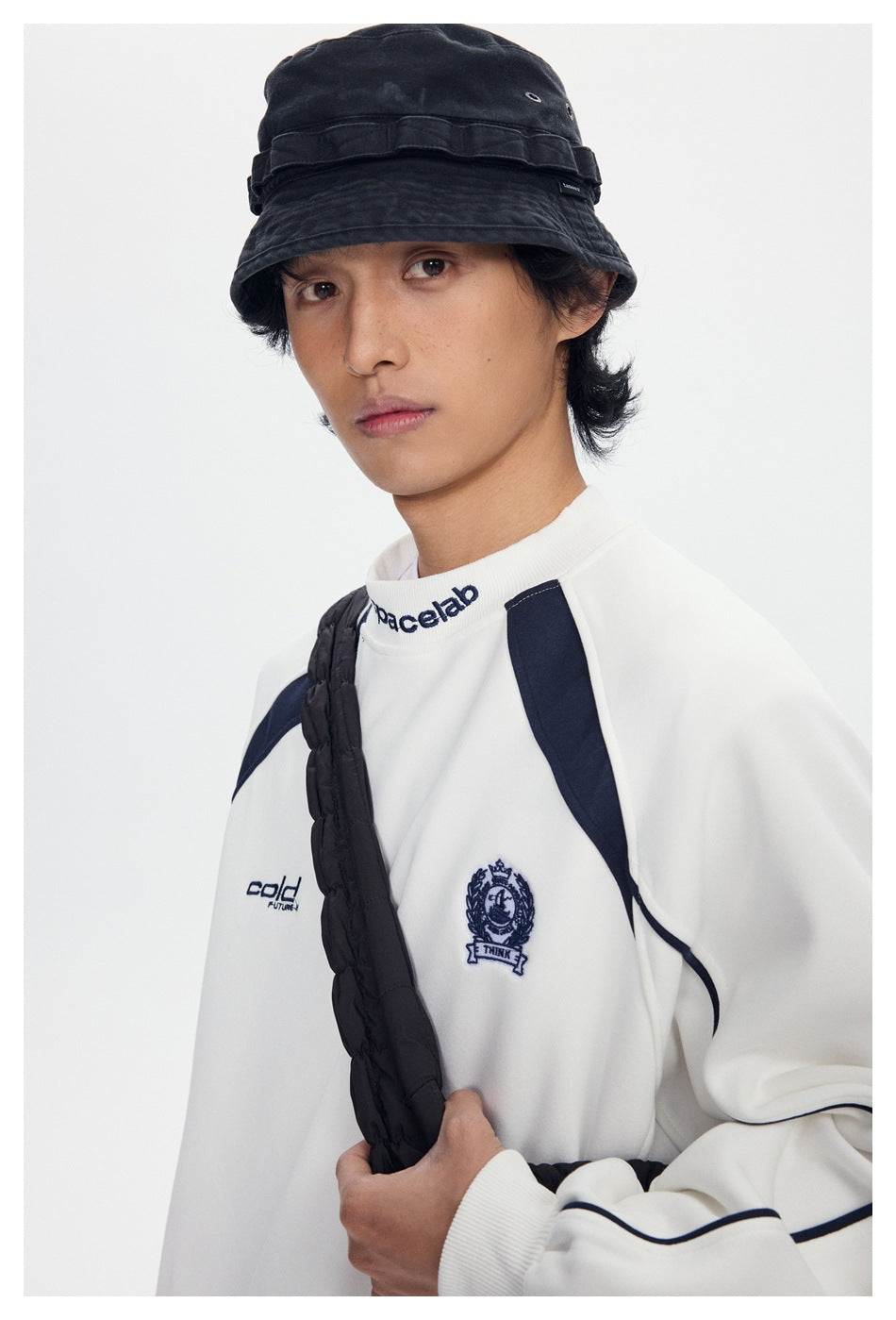 Angled close view of a model wearing a white sweatshirt with navy accents and chest graphics.