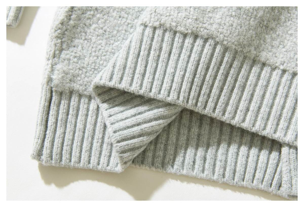 Close-up of the ribbed hem and textured knit of a light gray sweater.
