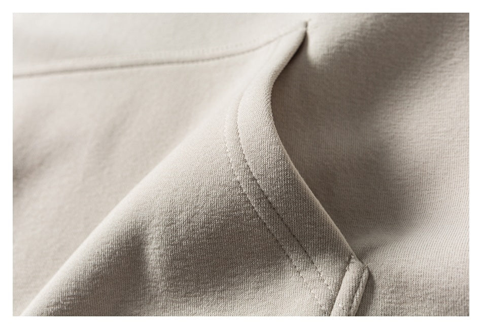 Close-up of cream hoodie fabric and a curved stitched seam.