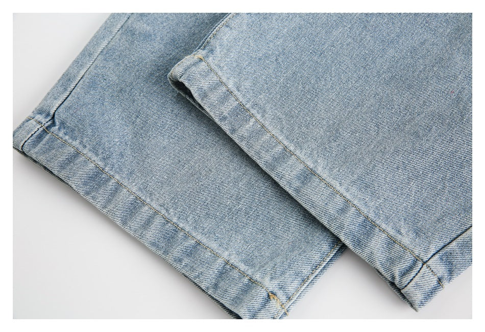 Close-up of the stitched hems of light blue denim legs laid overlapping on a white surface.
