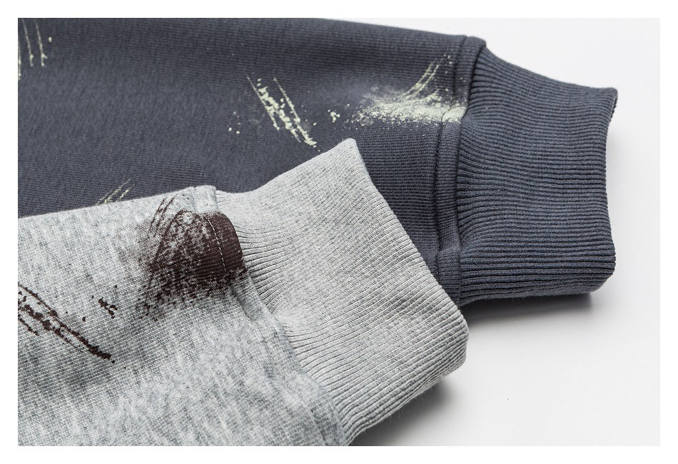 Close-up of ribbed cuffs on charcoal and gray sweatshirts, showing distressed printed marks near the cuffs.
