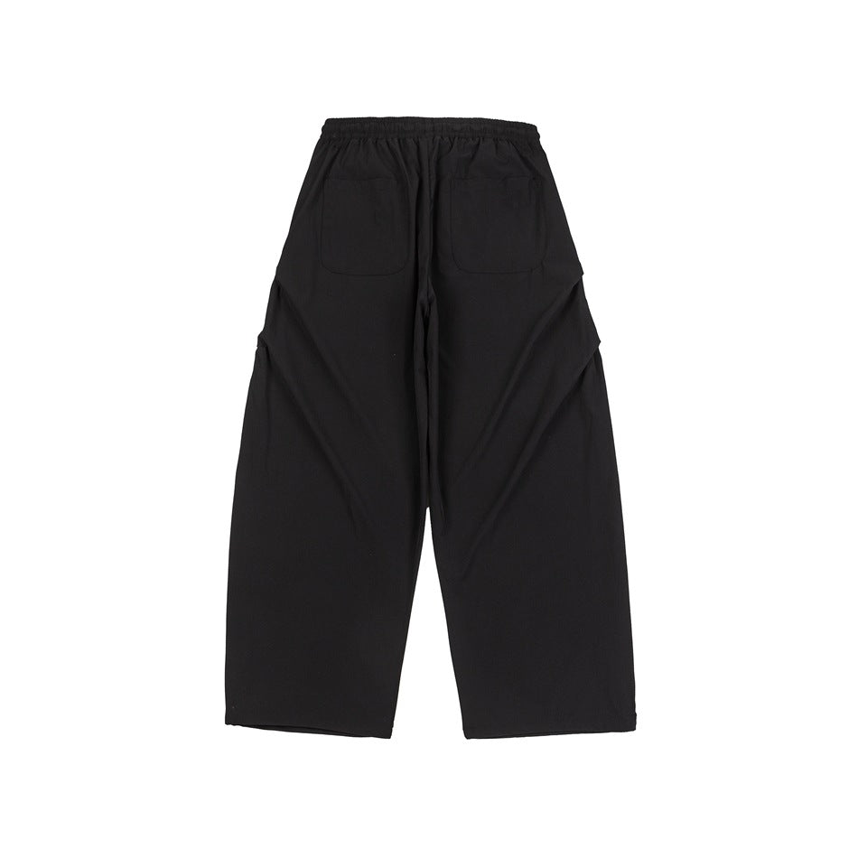 Black wide-leg pants back view showing elastic waistband and two patch pockets, flat lay