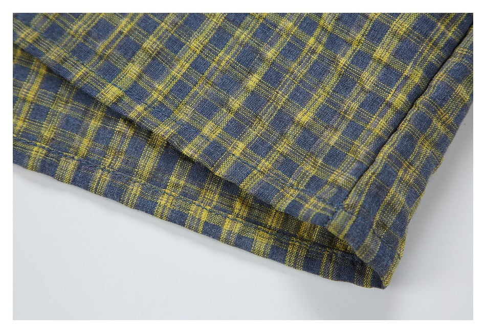 Close-up of the hem and stitching on a blue-gray and mustard plaid shirt.