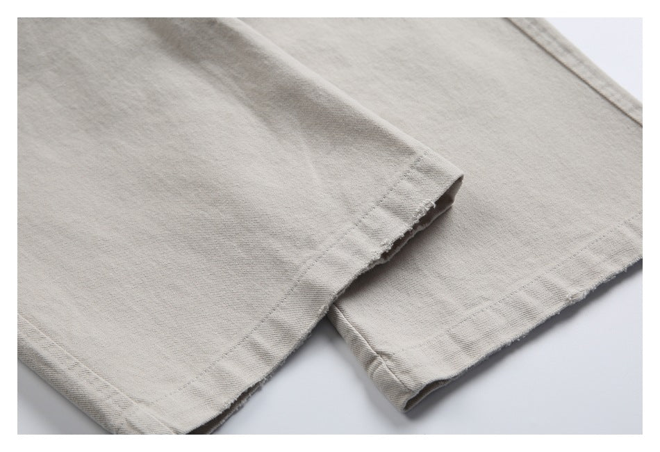 Close-up of beige trousers showing double-stitched hems with slightly frayed edges.
