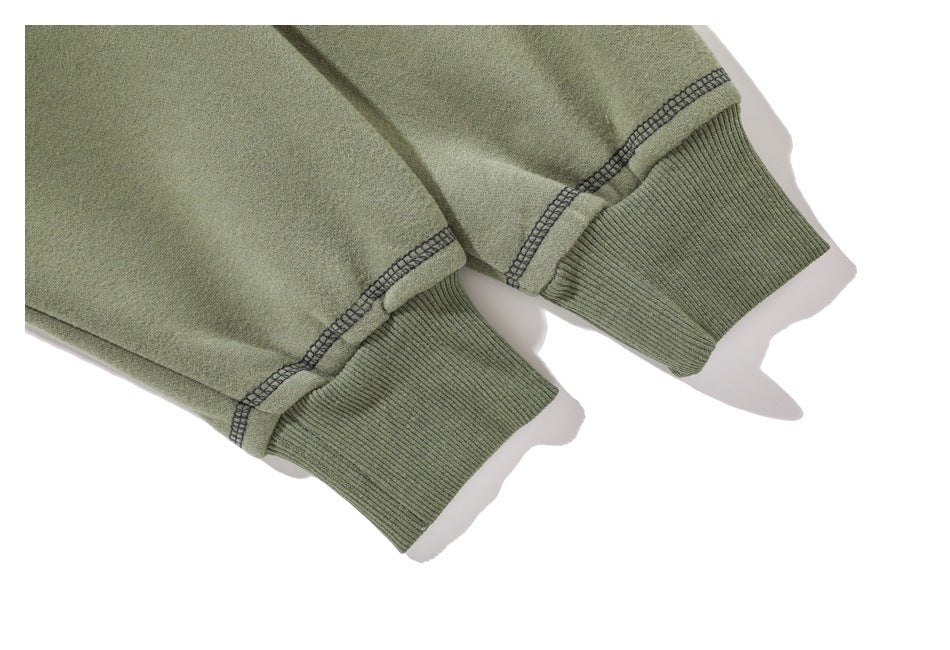 Close-up of the olive green hoodie’s ribbed cuffs and contrasting overlock stitching.