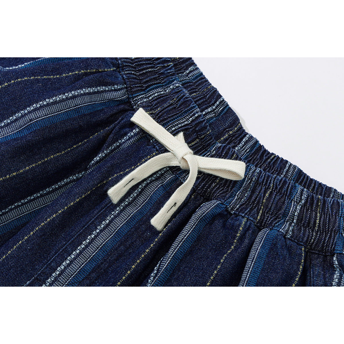 Close-up of dark blue striped trousers with a gathered elastic waistband and cream drawstring.