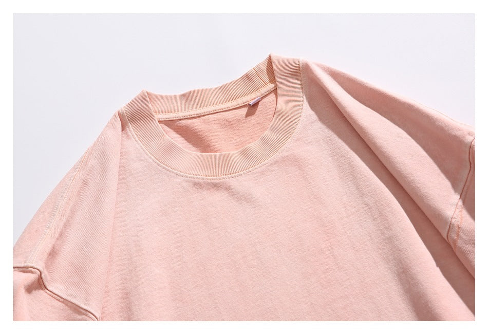 Close-up of a peach T-shirt showing its ribbed crew neckline and shoulder seams.