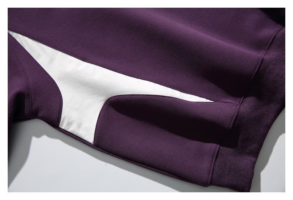 Close-up of a white side panel bordered by plum fabric, with the sweatshirt's ribbed hem visible.