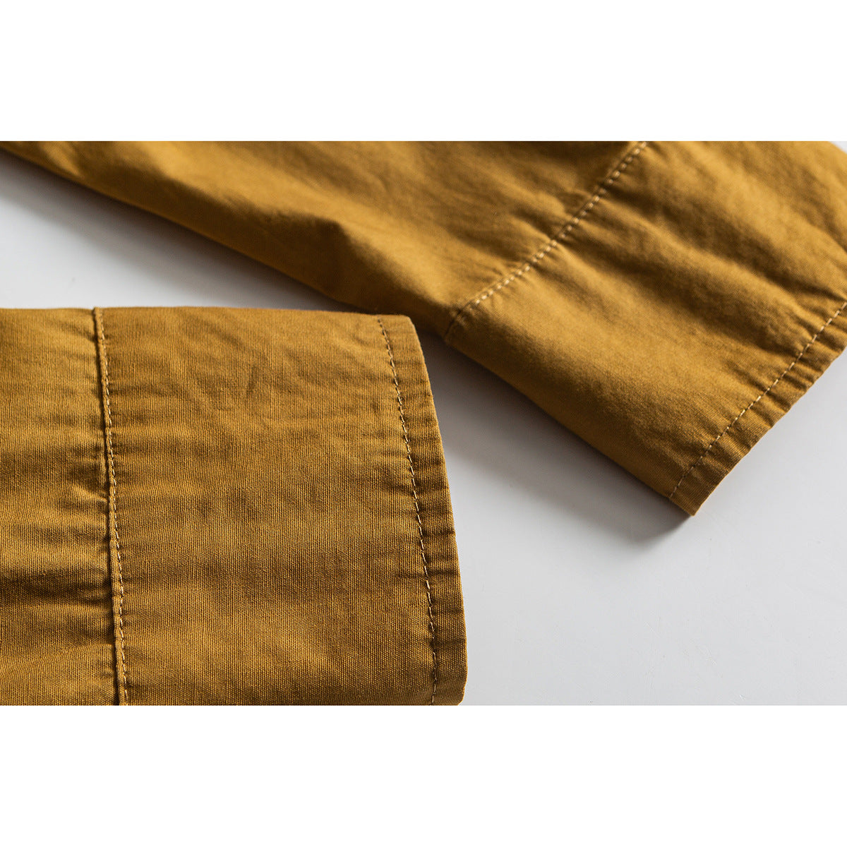 Close-up of a mustard shirt's sleeve and cuff, showing the stitching and fabric texture.
