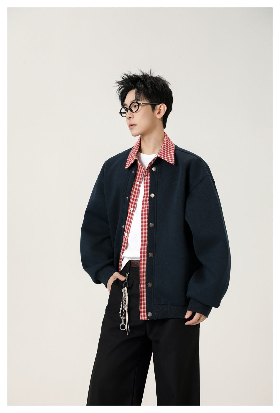 Model wearing an oversized navy snap-front jacket over a red checked shirt and white tee.